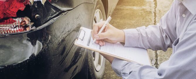 Auto insurance agent inspecting car damage for claim