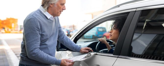 A driver discussing car insurance coverage with an agent from Tomneedham Insurance while reviewing vehicle documents in Greensboro