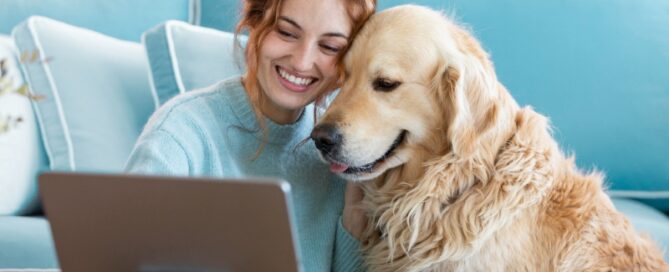 Woman sitting with her Golden Retriever while using a tablet, highlighting pet insurance from Tomneedham Insurance in Greensboro